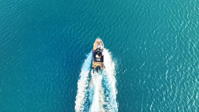 Aerial drone top down tracking video of small inflatable rib speed boat cruising in mediterranean sea