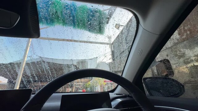 Point of view shot from inside a car passing through an automatic car wash.