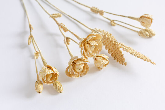 Three flowers are made of straw on a white background