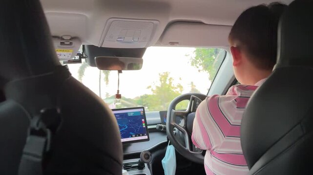 East Asian man driving and checking GPS map during the day.