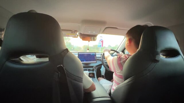 East Asian man driving and checking GPS map during the day.