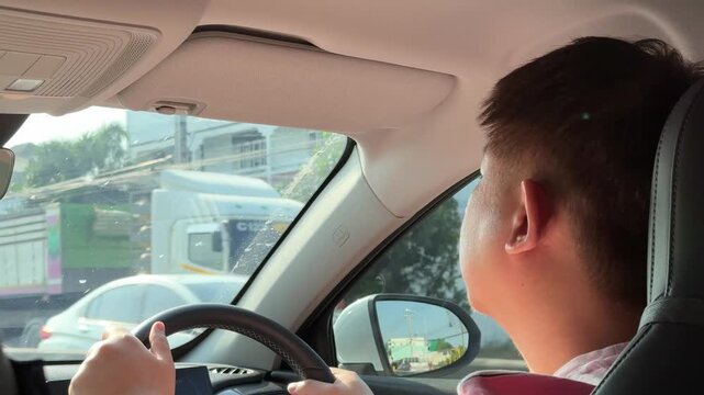 East Asian man driving and checking GPS map during the day.