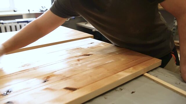 Master carpenter, Applying natural oil on natural wood product. A joiner applies a wood impregnation to a wood product. Carpenter applying protective varnish to wooden surface in workshop