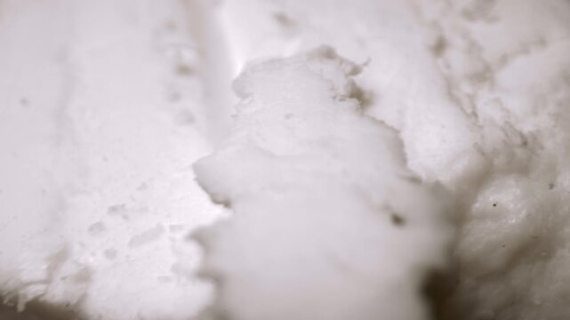 Extreme close-up hands sculpting in a block of white porcelain to craft handmade pottery. Chiseling off chunks of the porcelain clay