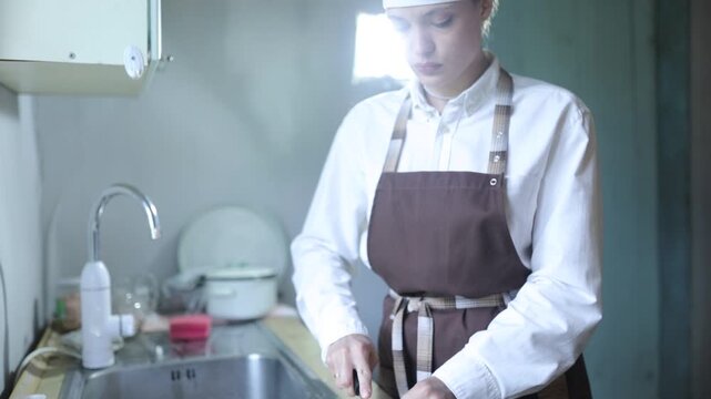 A female chef cooks in the kitchen at home wearing a chef's costume