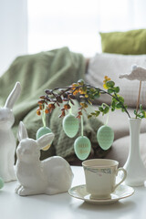 Obraz premium Spring Table Decor with Bunny Figurines, Hanging Eggs and Floral Cup of Coffee