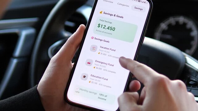 Managing Personal Savings Goals on Smartphone in Car. Close-up of a person tracking savings for vacation, emergency, and education funds on a sleek mobile app. High-quality UI design illustrating