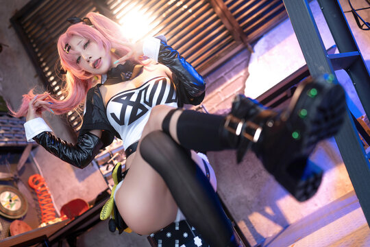 Cosplayer in pink wig and black outfit poses playfully indoors