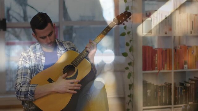Male musician plucking guitar strings and tuning pegs for perfect tone under drifting bokeh lights