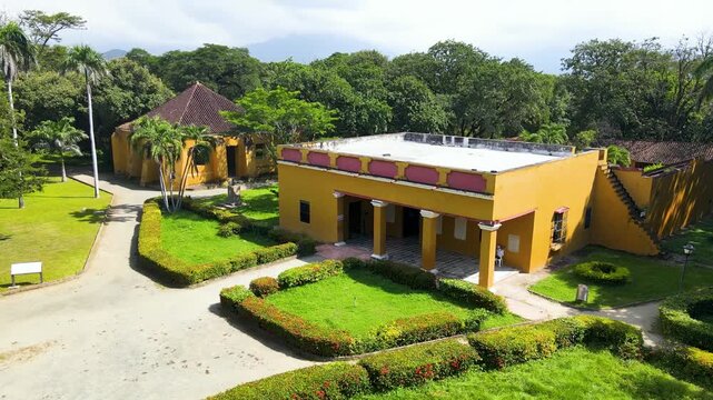 Aerial shot shows a yellow colonial house with tiled roof, palm trees and manicured hedges framing pathways at Quinta de San Pedro Alejandrino.