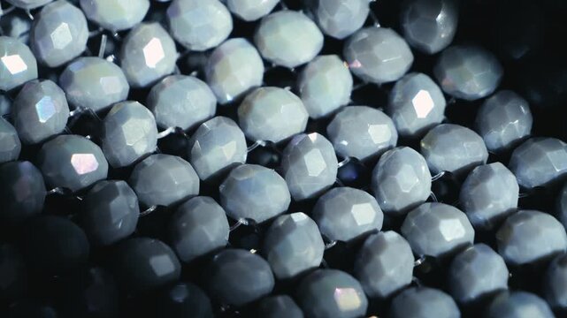 A close-up of a hand-beaded handbag with detailed bead texture. Fashionable, structured accessories highlight the glossy surface and intricate craftsmanship. High quality 4k footage
