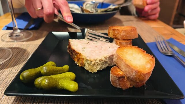 An exquisite terrine made from pork and foie gras, pistachios, and apricots, elegantly served with toasted crispy baguette slices and pickled cornichons. French cuisine concept. High quality 4k