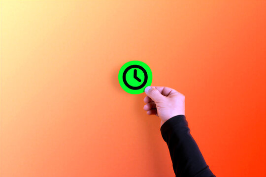 Hand holding green clock icon on orange background