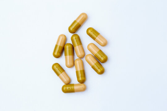 Macro close-up of multiple anthelmintic gelatin capsules scattered on white surface, pharmaceutical deworming medication concept