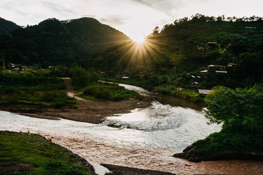 Beautiful sunstar over the Sapan river and mountains in Nan province, Thailand. Majestic sunrise over Sapan river with golden light reflecting on the water. 