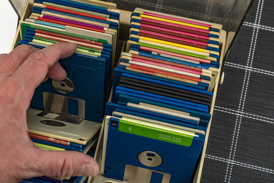 A box of old 3.5-inch floppy disks, colorful floppy disks for 8-bit computers from the 1990s, a collection of old computer games on floppy disks,