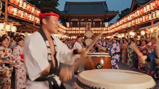 A video showcases two drummers performing in front of a large crowd at a traditional Japanese festival in a historic temple setting.