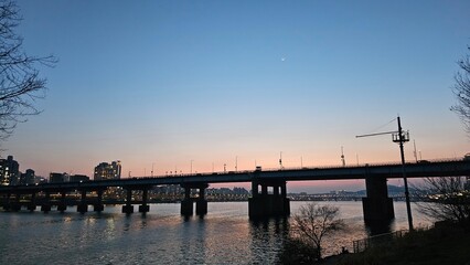 Obraz premium Han River bridge at sunset with silhouette trees 서울 한강 노을과 다리 실루엣 풍경