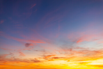 Fototapeta premium Vibrant sunset sky with orange and purple clouds background,Beautiful dramatic sunset sky with colorful clouds in shades of orange, pink, and deep blue. High resolution golden hour sky background for 