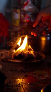 Close-up of a traditional small havan (holy fire) and a glowing clay diya at home during Navratri, featuring a bright flame and smoke in a dark, spiritual setting.