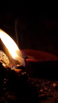 Close-up of a traditional small havan (holy fire) and a glowing clay diya at home during Navratri, featuring a bright flame and smoke in a dark, spiritual setting.