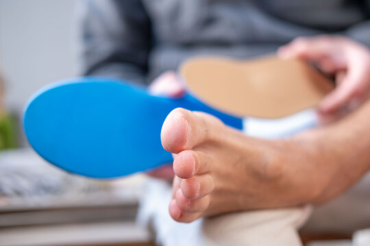 Man trying orthopedic shoe insoles on bare foot, fitting medical arch support insert, Podiatry and foot health prevention, foot care and podiatry concept, choosing comfortable support for walking
