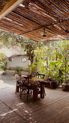 Fototapeta premium Rustic Outdoor Dining Area with Wooden Furniture in Lush Tropical Garden