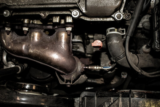 looking down at a car's engine bay, including the oxygen sensor installed in the exhaust manifold. automotive background.