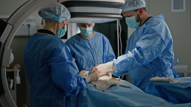 Pull out shot of surgery team gathering around operating table, cooperating with each other while performing surgery