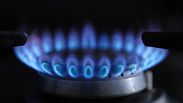 Blue flames from gas stove burner gradually intensify and spread in a close-up view, symbolizing rising oil prices, energy market volatility, increasing fuel costs and inflationary pressure