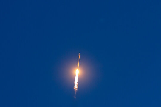 Space rocket with satellites launching against clear blue sky with trail of flame, aerospace program of China.