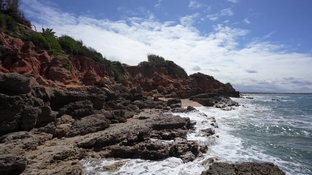 Rocky Cliffs and Sandstone Formations on the Coast of Chiclana Spain; Scenic Atlantic Ocean Waves Crashing Against Rocks at La Barrosa Beach in Andalusia with Blue Sky Establishing Shot