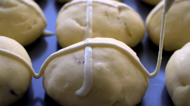 Decorate the bun with a religious cross made of flour. Hot Cross Buns  close‑up,  brioche de Vendredi Saint, mazanec, Good Friday, Easter tradition. Step-by-step preparation of homemade traditional Ea