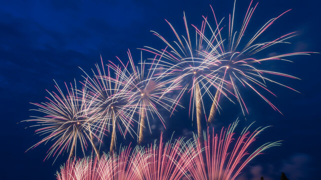 Fireworks exploding in the night sky with pink and white sparks