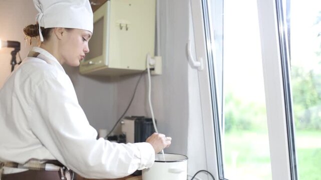 A female chef cooks in the kitchen at home wearing a chef's costume