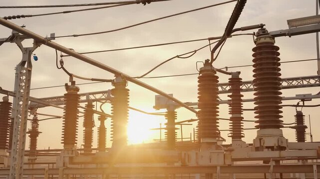 Electric power substation equipment with high voltage insulators and wires during sunset