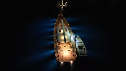 Aerial drone night shot of illuminated sail boat with wooden deck anchored in deep blue Aegan sea © aerial-drone
