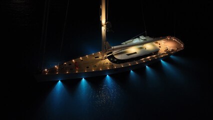 Aerial drone night shot of illuminated sail boat with wooden deck anchored in deep blue Aegan sea © aerial-drone
