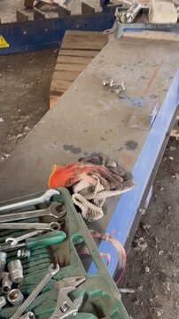 A close-up view of a toolbox filled with wrenches and sockets, alongside work gloves resting on a metal surface