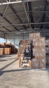Rows of wooden crates filled with white building blocks are neatly stacked inside a large industrial warehouse