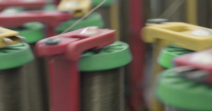 Braiding equipment, machine for weaving ropes, cables or wires is working, bobbins are moving. Close-up handheld shot, real time speed.