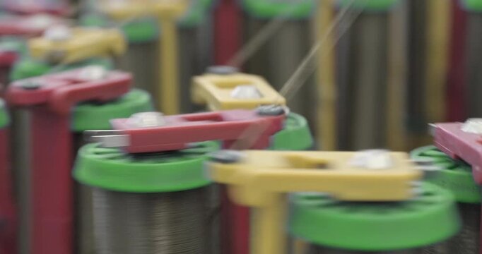 Braiding equipment, machine for weaving ropes, cables or wires is working, bobbins are moving. Close-up handheld shot, real time speed.