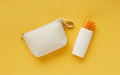 Obraz premium A white cosmetic pouch and sunscreen bottle on a yellow surface
