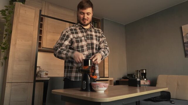 A male householder cuts carrots on a vegetable slicer