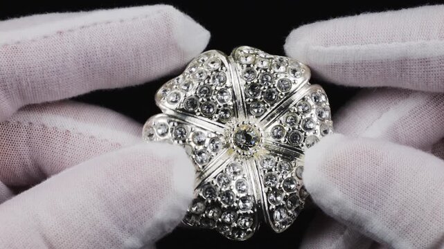 Large flower-shaped brooch made of silver-colored metal with transparent sparkling crystals. Elegant vintage fashion accessory with shining rhinestones.