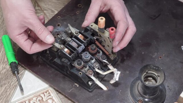 A disassembled machine with copper coils in the hands of an electrician, Dismantling and repairing an old three-phase magnetic starter