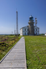 Obraz premium Lighthouse building on a sunny day with a wooden boardwalk leading to it