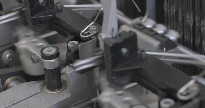 Spinning equipment, weaving machine, the jacquard loom is working. The parts of the mechanism move rhythmically, performing reciprocating movements. Close-up handheld shot, real time speed.