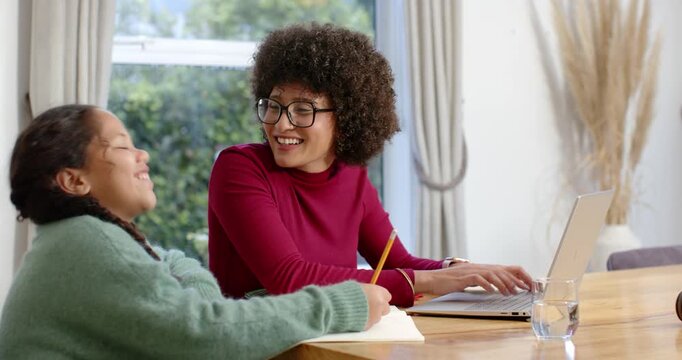 African American family at table, daughter asking and father bringing coffee, pointing at laptop
