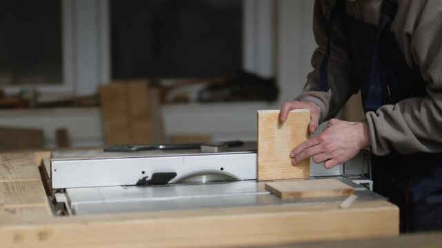 A woodworker carefully positions a piece of wood on a table saw. An artisan prepares to cut lumber in a professional workshop.